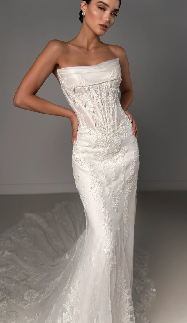 Photo of the model wearing a bridal gown and posing near the sofa